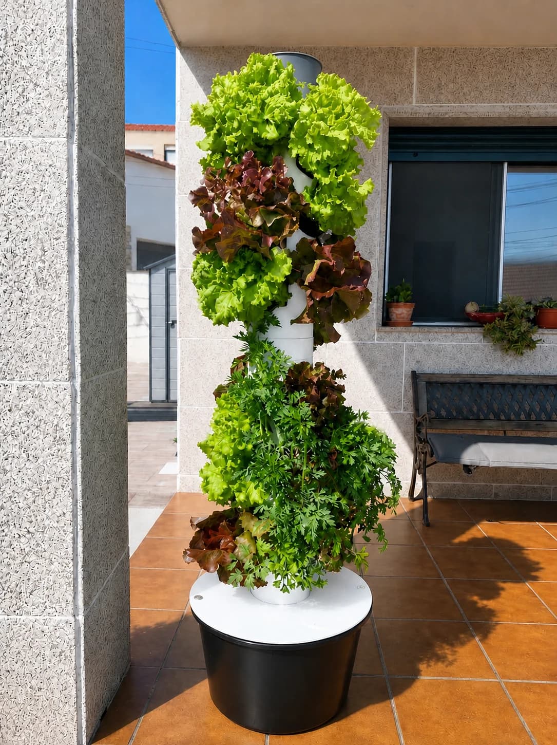 Torre hidropónica Bonxur limpia con lechugas verdes y rojas en una terraza soleada